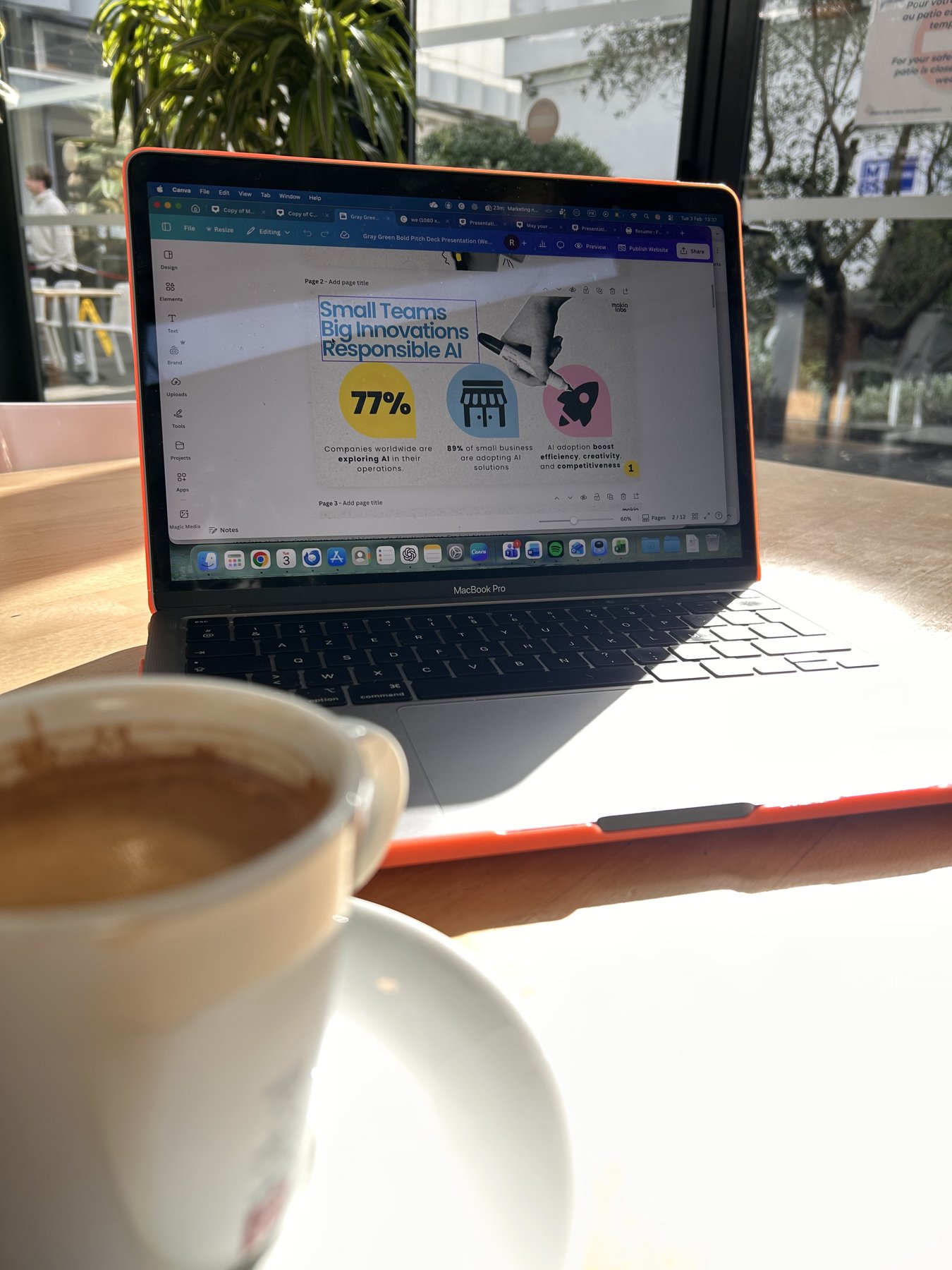 A MacBook showing an AI adoption slide next to a coffee cup on a sunlit cafe table